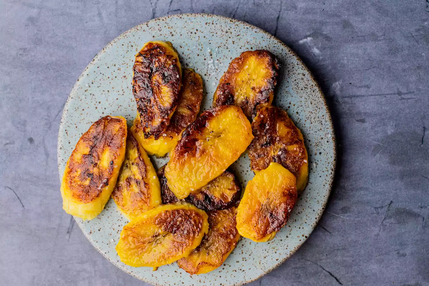 Several lightly charred plantain slices on a plate