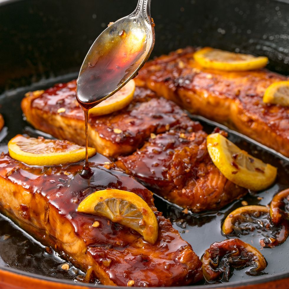 Salmon topped with lemon slices, glaze, and a spoon pouring glaze over the salmon